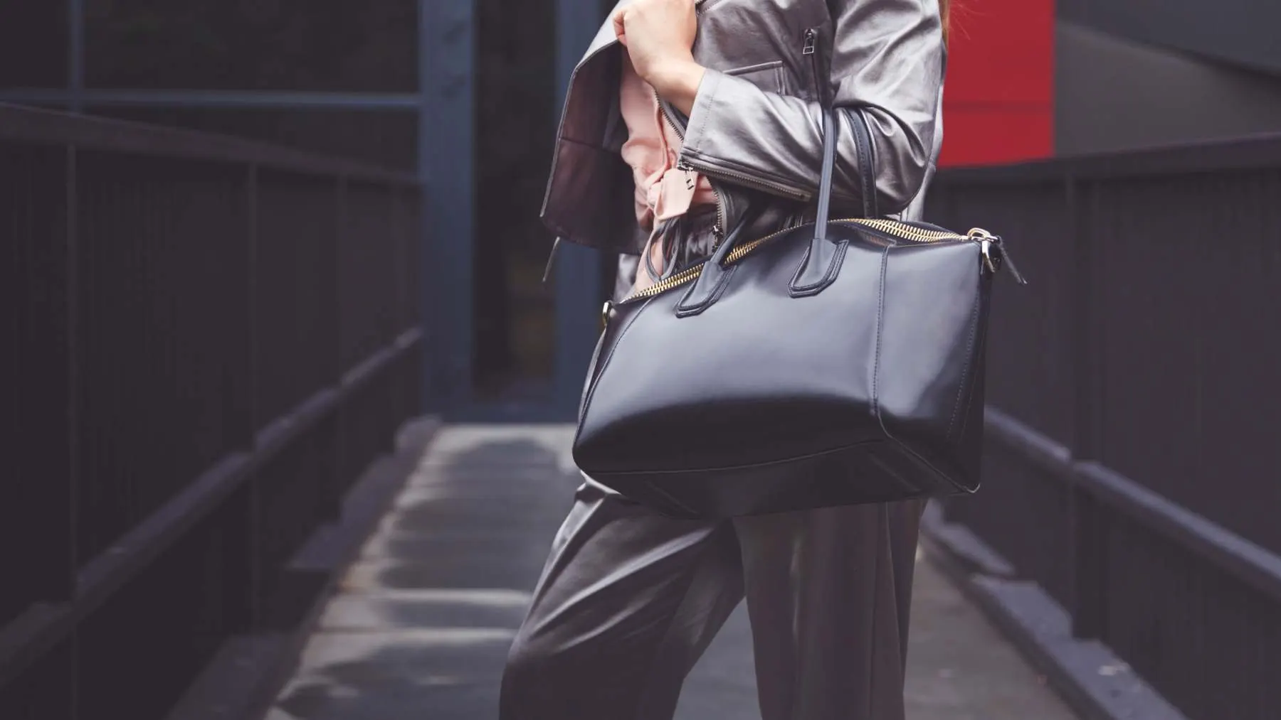 Woman carrying a restored black leather handbag, Leathermend handbag workshop